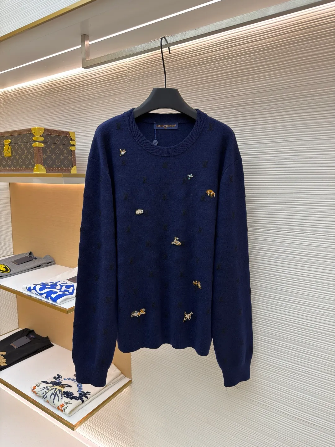 LOUIS VUITTON animal embroidered wool crew neck sweater ●Original version: purchased and developed by 18025 ●Item number: 1682089-B05 ●Fabric: wool blended fabric ●Technology: knitted embroidery production ●Color: navy blue ●Version: fitted version ●Weight: about 590 grams ●Size: XS-S-M-L ●Description: This Louis Vuitton navy blue sweater is made of ultra-fine merino wool blended yarn and is knitted by worsted knitting technology. It uses 16-needle high-density plain knitting technology to give the fabric a silky delicate touch and matte texture. The base of the body is also woven with a mini Monogram pattern using a same-color dark jacquard technology. The pattern is low-key and naturally blends with the wool texture. The decorative details embellished on the body are made of hand-made beading and metal veneer inlays. The veneer is aged by electroplating and enamel color-filled. Every decoration is hand-positioned and sewn by craftsmen to ensure firmness and a beautiful arrangement. The round neckline adopts double-needle overlock knitting technology, which is not easy to deform and fits the neck. The side seams and hem of the body use seamless splicing technology to reduce friction when wearing. The overall stitching is even and fine, fully demonstrating the brand's exquisite craftsmanship and detail control in the field of knitted garments. The overall wiring is straight and delicate, the fabric is comfortable and soft, and the color is consistent without color difference. It can be matched with the same style to create a fashionable look and control various occasions. Customized accessories, complete with three standards, same style for men and women!